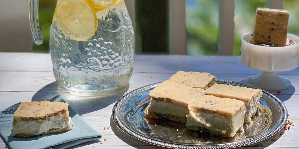 Butter Pecan Maple Ice Cream Sandwiches on a platter, napkin, and in a jar of sprinkles with a pitcher of lemonade nearby.