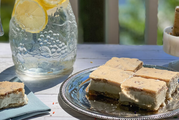 Butter Pecan Maple Ice Cream Sandwiches on a platter, napkin, and in a jar of sprinkles with a pitcher of lemonade nearby.
