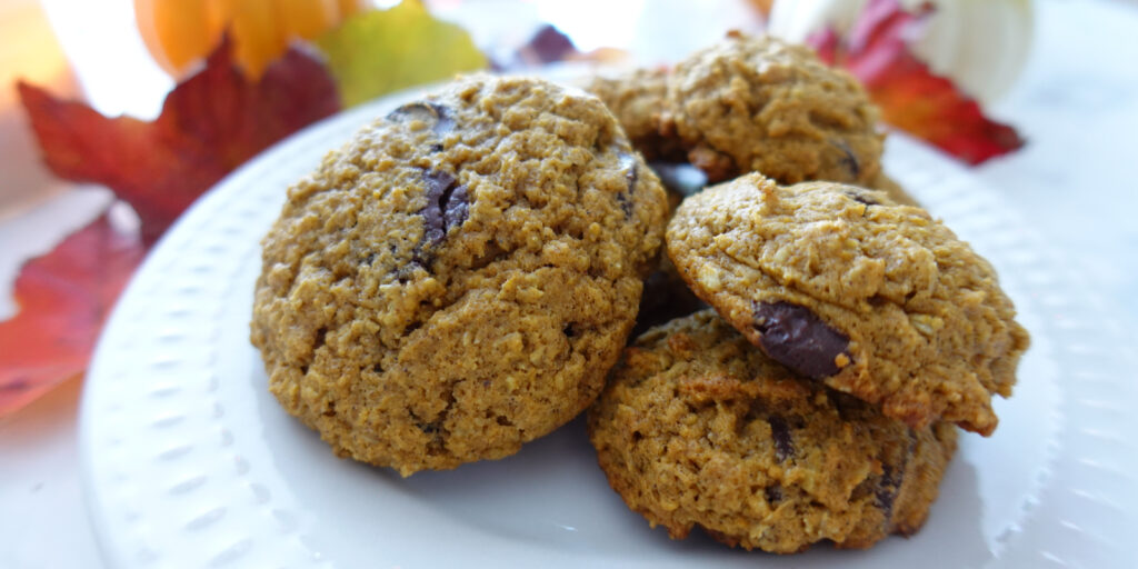 Pumpkin Oatmeal Chocolate Chip Cookies stacked on a plate in a fall setting.