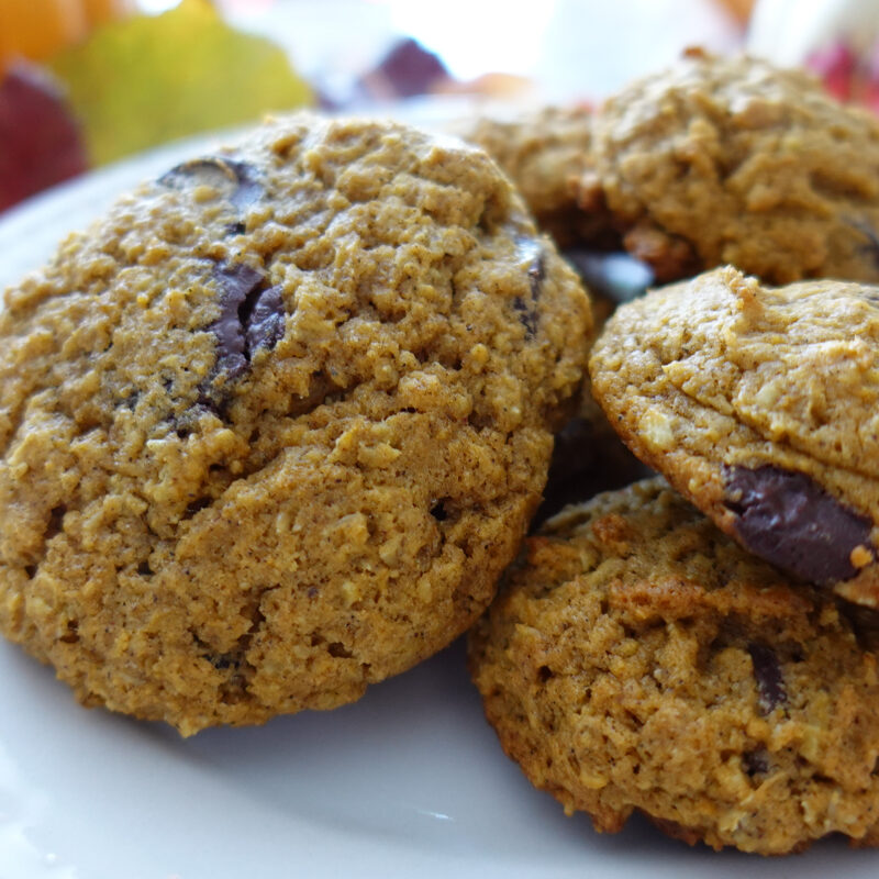 Pumpkin Oatmeal Chocolate Chip Cookies stacked on a plate in a fall setting.