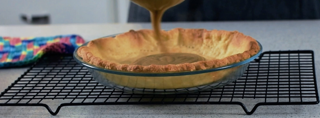 Image of butterscotch custard being poured into a pre-baked pie shell.