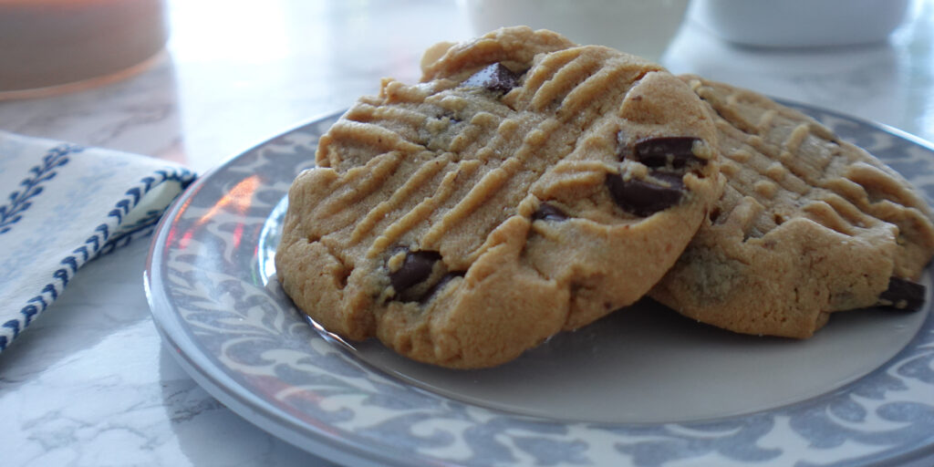 Two PB Chocolate Chip Cookies on a plate.