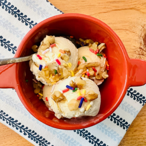 No Churn ice cream scooped in a bowl with nuts and sprinkles.