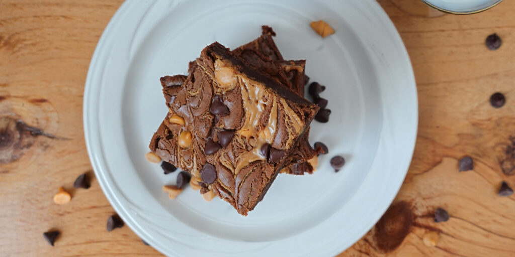 Chocolate Fudge Peanut Butter Brownies stacked on a white plate.