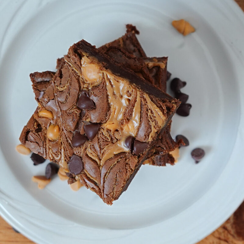 Chocolate Fudge Peanut Butter Brownies stacked on a white plate.