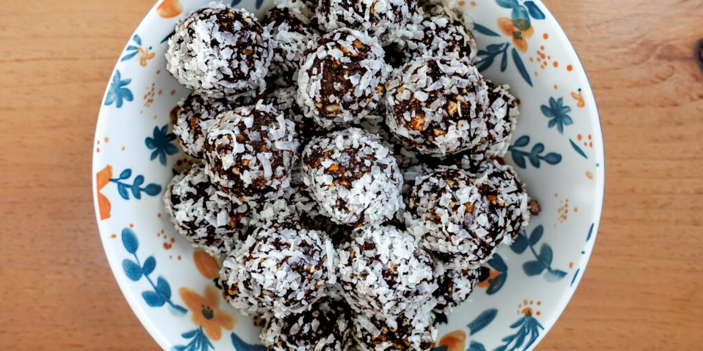 Vegan Energy Bites stacked in a bowl on a wooden table.