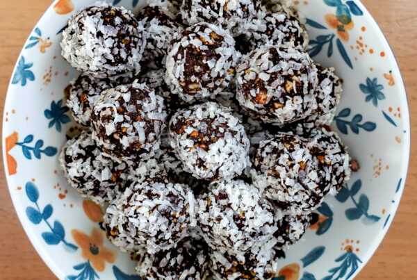 Vegan Energy Bites stacked in a bowl on a wooden table.