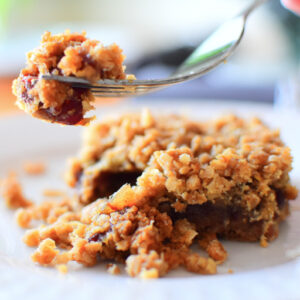 A Date Square on a plate with a piece of it on a fork suspended in the air.