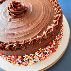 Birthday cake on a white cardboard over a blue surface.