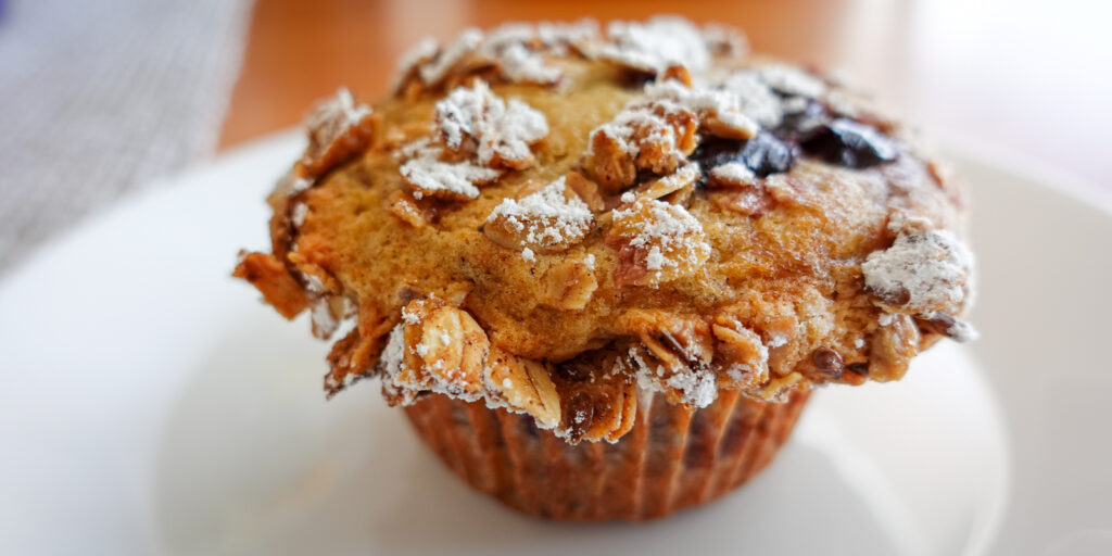 This recipe for cherry muffins creates beautiful mounds as evidenced by this image of a muffin on a white plate.