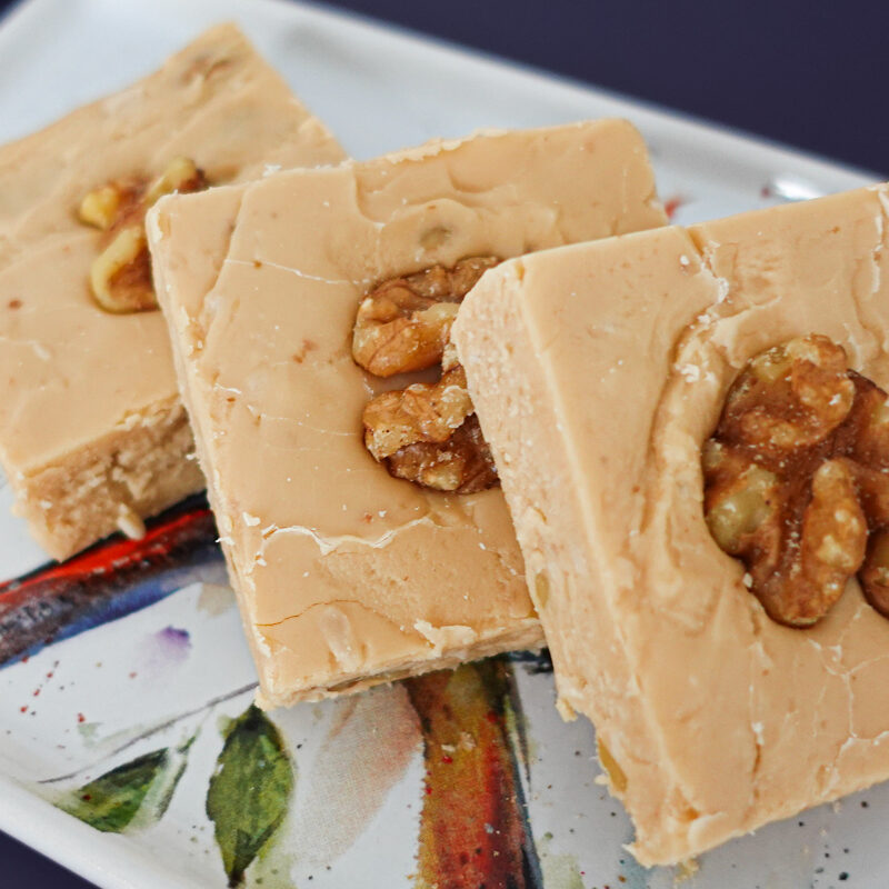 Penuche Fudge on a white plate on a blue backdrop.