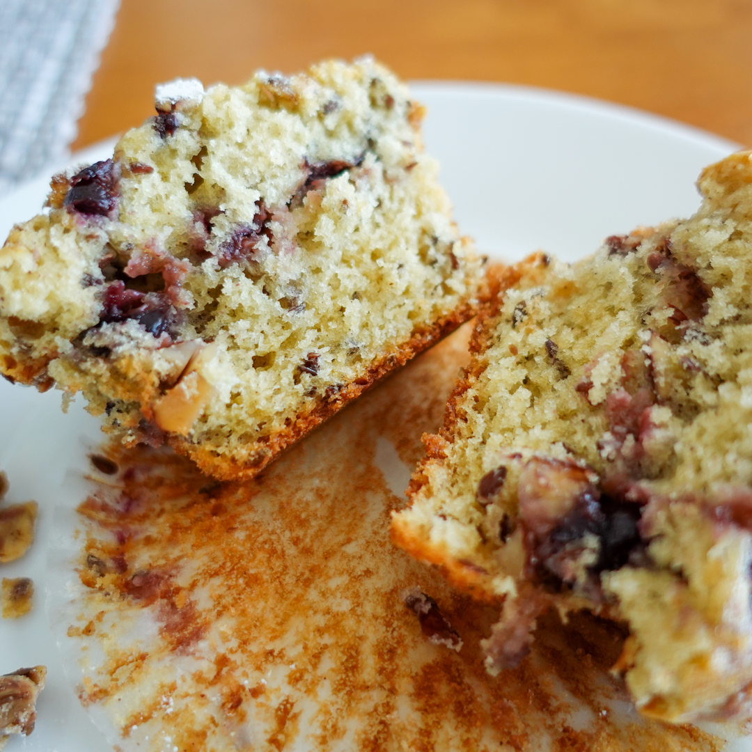 This recipe for cherry muffins creates a tender, moist crumb as evidenced by this muffin cut in half on a white plate.