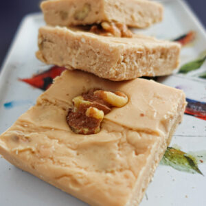 Three pieces of penuche fudge stacked on a small white plate.