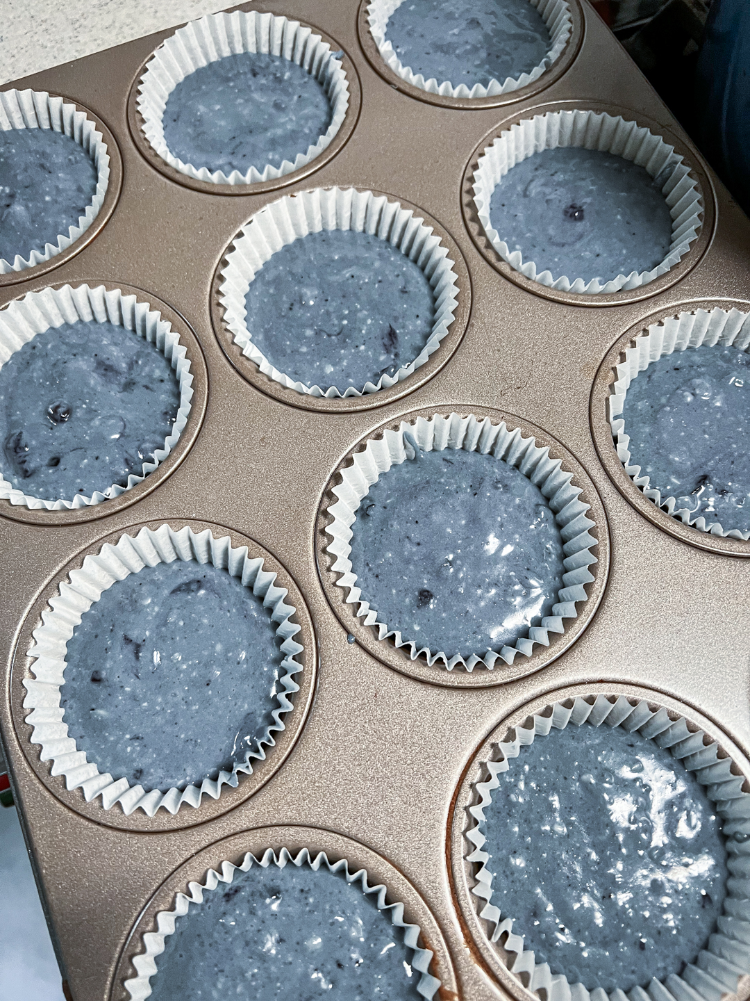 This is an image of a cupcake pan with liners filled 2/3 of the way full of batter.