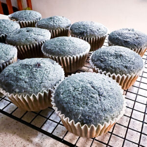 This is an image of blueberry cupcakes fresh out of the oven set on a cooling rack.