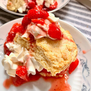 This is an image of a serving of strawberry shortcake that's homemade and on a white plate.