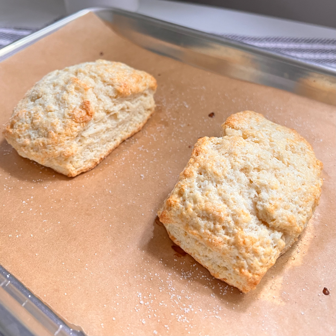 This is an image of two strawberry shortcake homemade biscuits on a parchment-lined baking sheet.