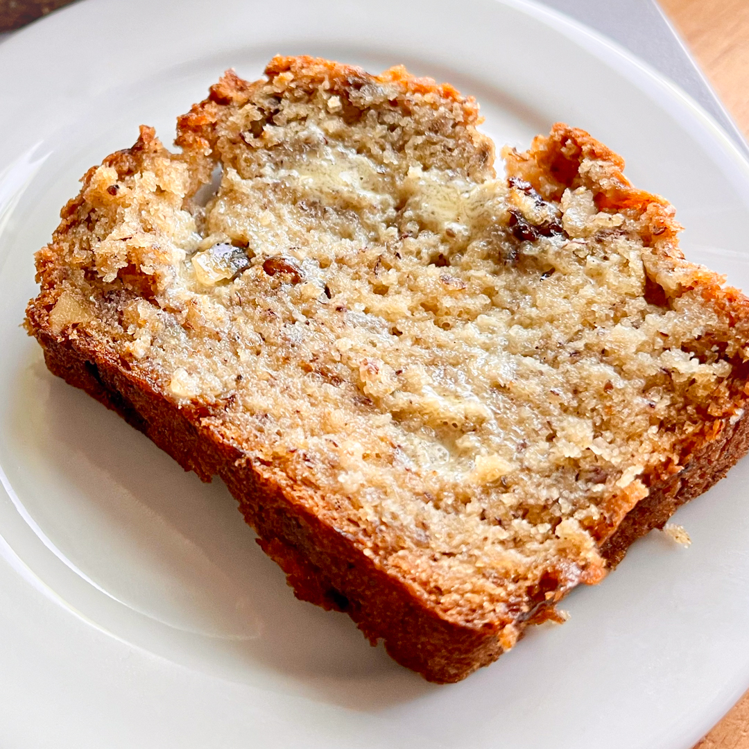 A slice of banana bread with oat milk butter spread on it.