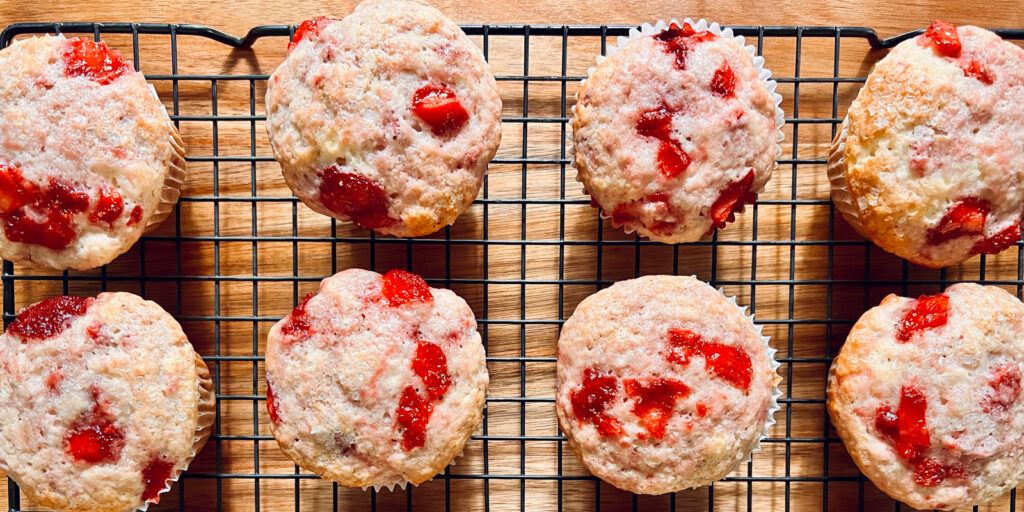 An image of strawberry muffins on a cooling rack.