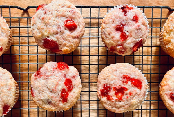 An image of strawberry muffins on a cooling rack.