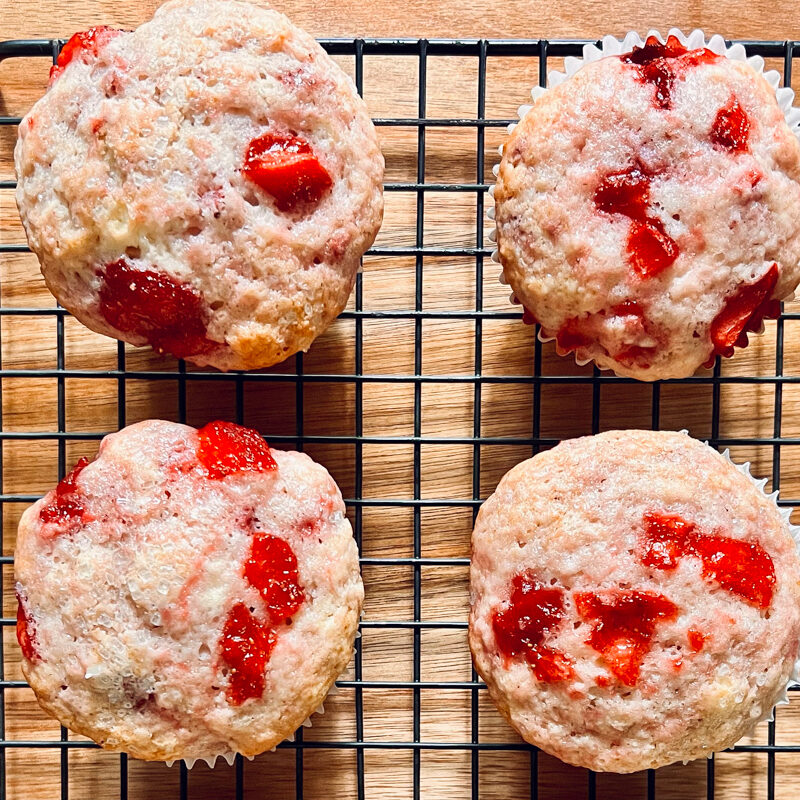 An image of strawberry muffins on a cooling rack.