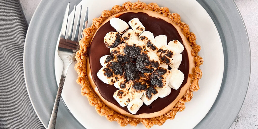 This is a top-down view of a peanut butter s'mores tart, which is on a white plate.