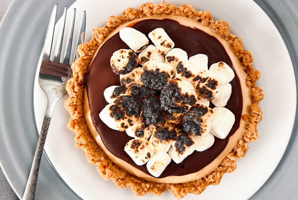 This is a top-down view of a peanut butter s'mores tart, which is on a white plate.