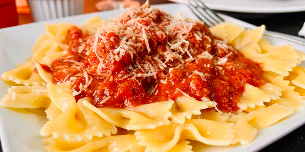 Meatballs and Pasta on a white plate with sauce.