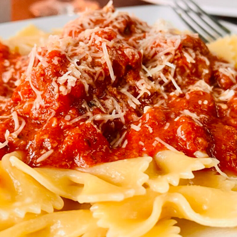 Meatballs and Pasta on a white plate with sauce.