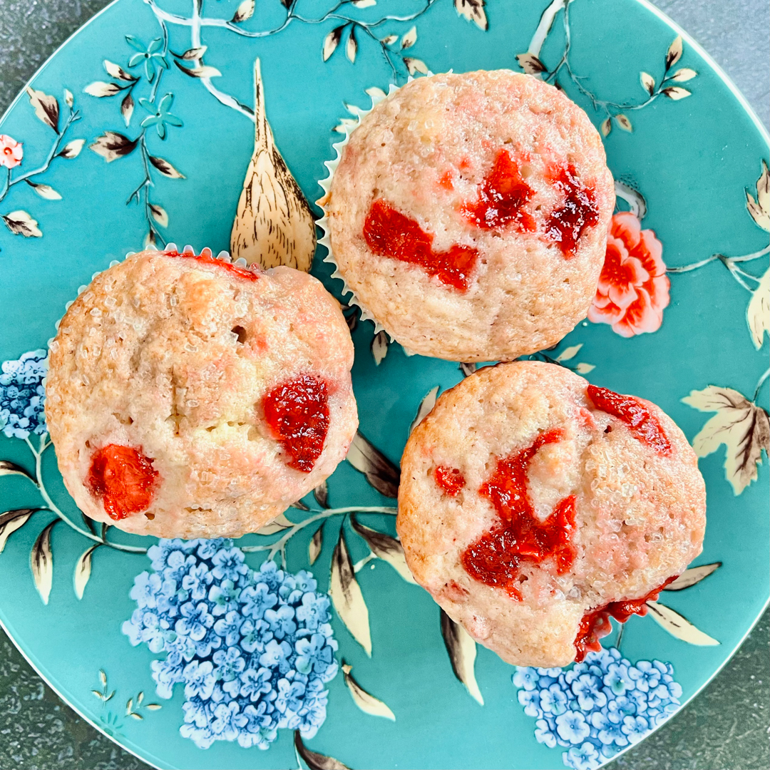 Top down image of three strawberry muffins on a decorative plate.