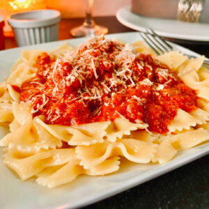 Italian Meatballs and Sauce over pasta on a white plate.