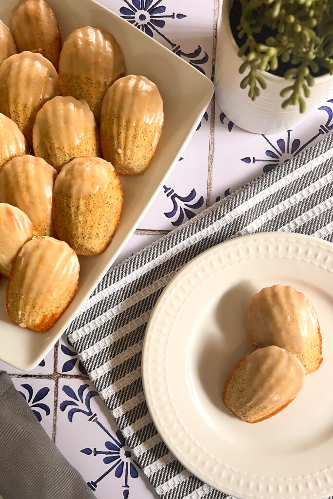 Maple-Earl Grey madeleine cookies resting on a white plate, showcasing its delicate shape and golden-brown exterior.