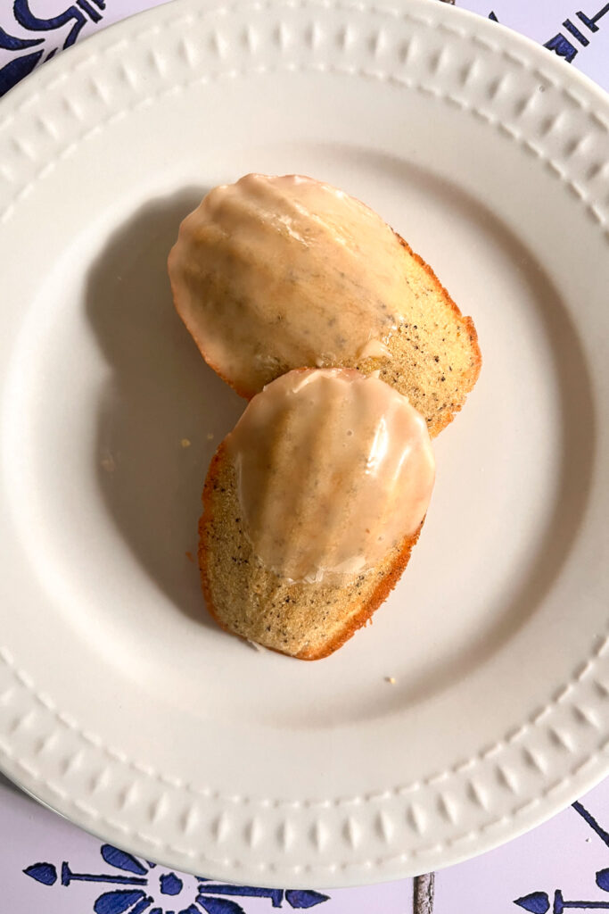 Maple-Earl Grey madeleines resting on a white plate, showcasing its delicate shape and golden-brown exterior.