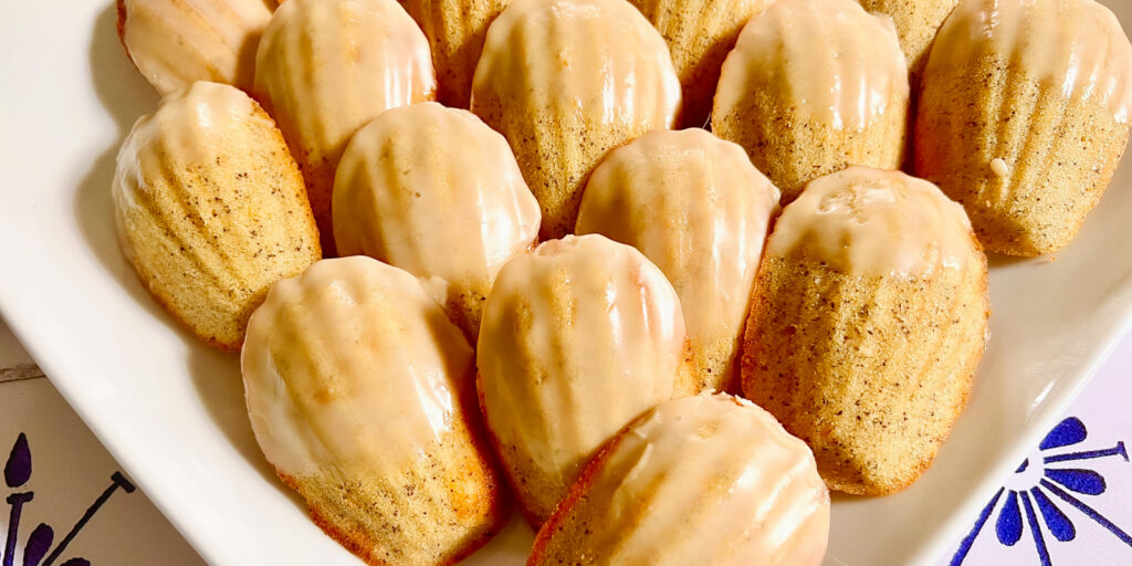 A tray of madeleines rest on a light countertop, showing off their golden exteriors.