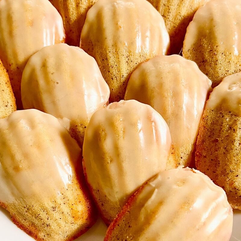 A tray of madeleines rest on a light countertop, showing off their golden exteriors.