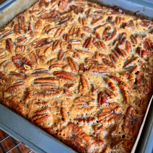 A closeup of pecan pie bars freshly made and still in the pan unsliced.