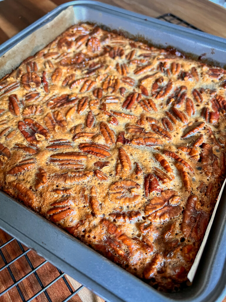 A closeup of pecan pie bars freshly made and still in the pan unsliced.