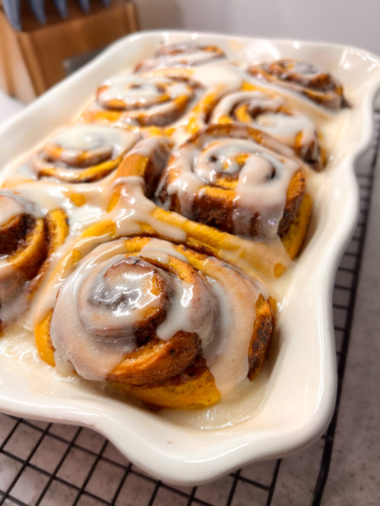 The pumpkin rolls freshly iced and still in their baking dish.